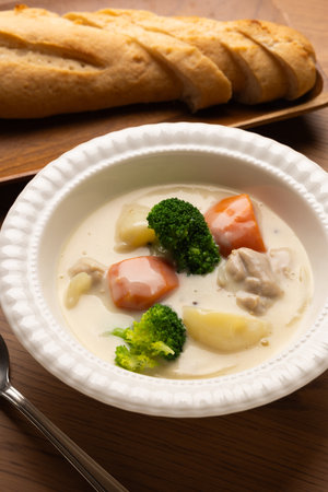 creamy stew with broccoli and potatoes in a white plate on a wooden tablesの写真素材