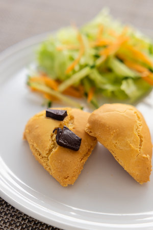 scorns topped with chocolate on a white plate with salad.の写真素材