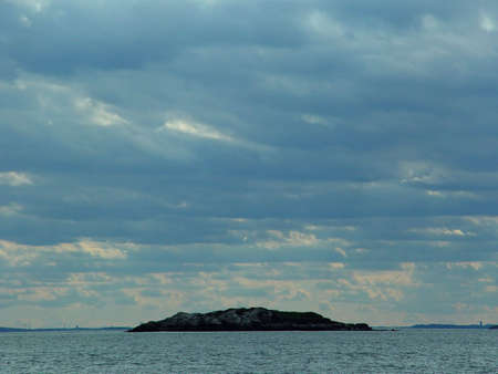 Small rock island in Massachusetts  seen in the distance from the sea shore.の写真素材