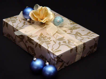 Gold gift box with blue and aquamarine ornaments and gold bow.