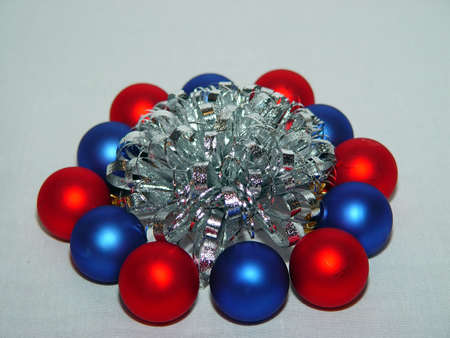 Various colored Xmas ornaments against a snowy background wrapped around a sliver bownの写真素材