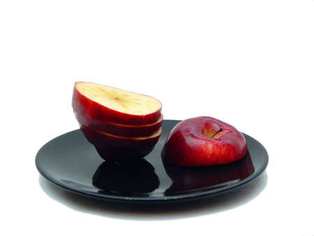 Sliced apple on black plate with white backgroundの写真素材