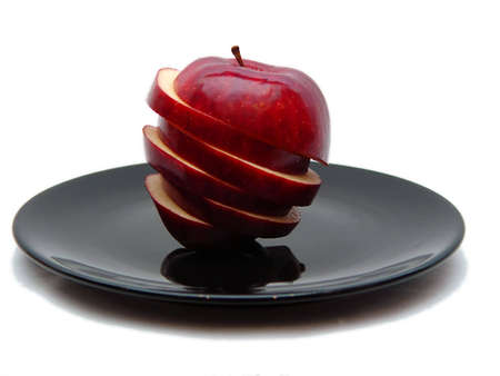 Sliced apple on black plate with white backgroundの写真素材
