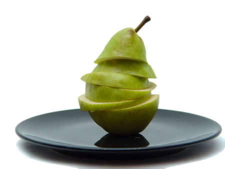 Sliced pear on black plate with white backgroundの写真素材