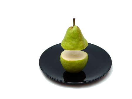Sliced pear on black plate with white background, top hovering above botomの写真素材