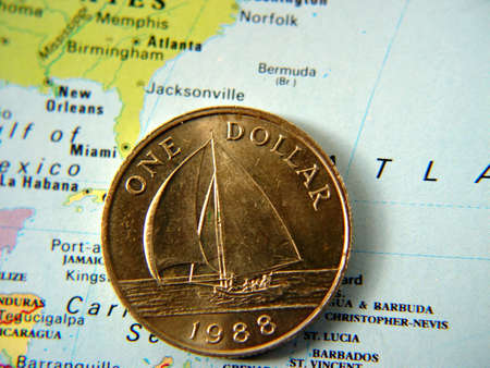 Bermuda one dollar coin on an atlas next to bermudaの写真素材