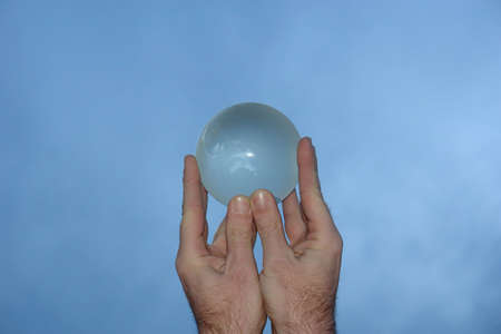 man holding crystal world globe to the sky in both handsの写真素材