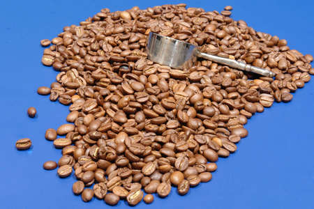 Coffee beans on blue with silver scoop