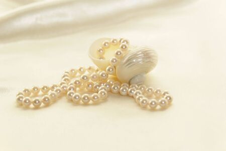 Beautiful white lustrous pearls against a soft white satin background.の写真素材