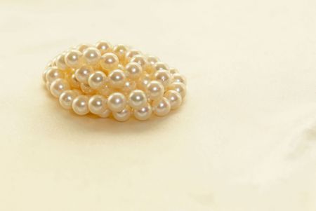 Beautiful white lustrous pearls coiledagainst a soft white satin background.
