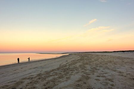 Sunset on Crane's beach in Ipswich Massachusetts with people at the shoreの写真素材