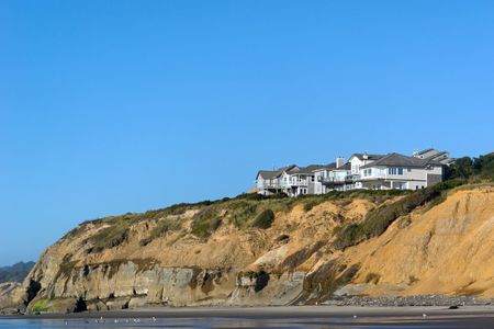 houses nestled on top of a sandy cliff on the coast of oregonの写真素材
