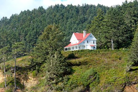 a cute white house stands out brightly against the mountainside, high upon a cliffの写真素材