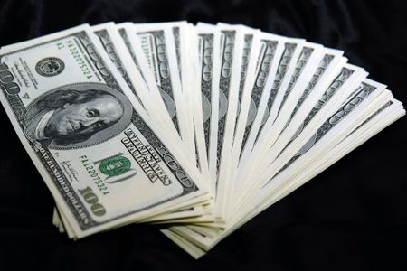 stack of USD fanned out on black satin background