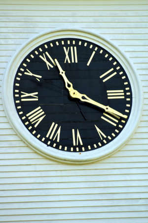 detail of public clock with gold roman numerals and a black faceの写真素材
