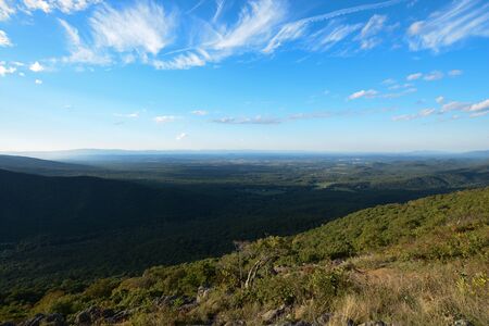 Valley view from mountain top with blue skies and cloudsの写真素材