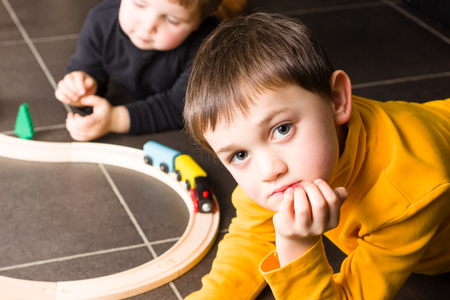 Children playing with wooden toy train. Brothers build wooden railroad at home.の写真素材