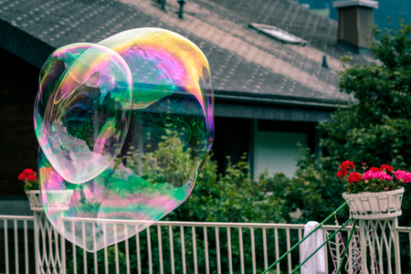 2 big rainbow soap bubbles flyining in the air on a garden backgroundの写真素材