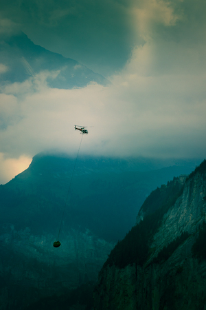 Helicopter carrying construction materials flying in the Bernese Alps, Jungfrau region, Switzerland.の写真素材