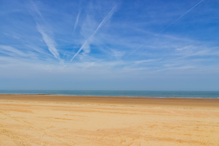 An empty beach with gold colored sand under a blue sky with some clouds on a sunny bright day. Ostend, Belgium, Europeの写真素材