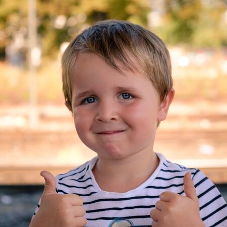 4 year old boy giving a double thumbs up. outside