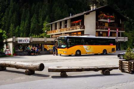 Zinal, Valais, Switzerland - August 7 2018 : a yellow PostAuto bus and picking up tourists in the alpine village Zinal at the end of the Val d' Anniviers valley in the southern canton of Valais.のeditorial素材