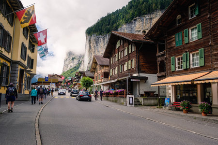 Lauterbrunnen, Berner Oberland, Switzerland - July 29 2019 : Tourists strolling in the charming main street of the picturesque swiss village in the Jungfrau region on a overcast day in summer - the famous Staubbach waterfall in the backgroundのeditorial素材