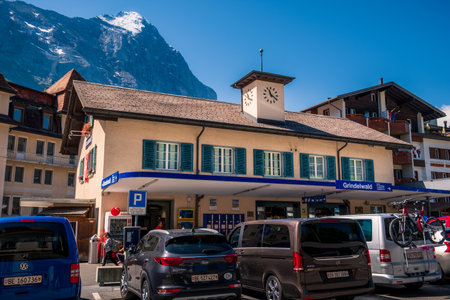 Grindelwald, Bernese Oberland Switzerland - July 30 2019: Main railway station building on bright summer day with clear blue sky and famous Eiger north face in the backgroundのeditorial素材