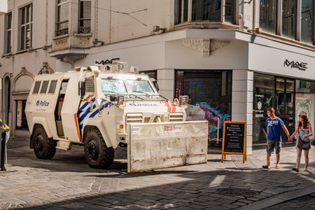 Ghent, Flanders, Belgium - July 15 2018: white armored riot truck with front clearing blade of Belgian police parked on the corner of a street downtown while a young couple passes byのeditorial素材