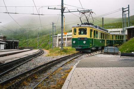 Kleine Scheidegg, Bernese Oberland, Switzerland - July 31 2019: Old electrical green and yellow train of the Wengernalpbahn (WAB) with pantograph up in the Kleine Scheidegg railway stationのeditorial素材