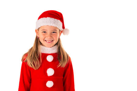 Portrait of beautiful 8 year old girl smiling and wearing red christmas costume with red dress and a Santa Claus hat isolated on whiteの写真素材