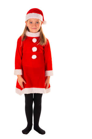 full length portrait of beautiful 8 year old girl standing with arms next to body wearing red christmas costume with a red dress, Santa Claus hat and black stockings isolated on whiteの写真素材