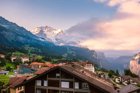 Panoramic view on the picturesque car-free alpine village Wengen. The snow capped mountain Jungfrau and cliffs of the Lauterbrunnen valley in beautiful morning light in the backgroundの写真素材