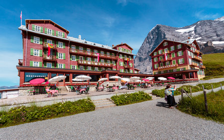 Kleine Scheidegg, Bernese Oberland, Switzerland - August 1 2019: Hotel Bellevue des Alpes and tourists enjoying the view on bright summer day with famous majestic Eiger north face in the backgroundのeditorial素材