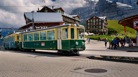 Kleine Scheidegg, Bernese Oberland, Switzerland - August 3 2019: Old electrical passenger train from WAB in the Kleine Scheidegg station, side Grindelwald and tourists strolling in the backgroundのeditorial素材
