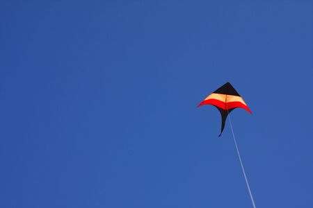 Colorful kite flying in a clear blue skyの写真素材