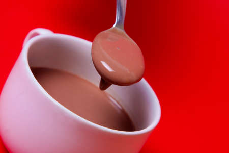 Hot chocolate with spoon with a red backgroundの写真素材