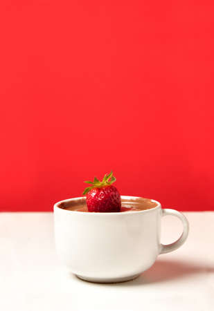 cup of hot chocolate with strawberry on a red background and whiteの写真素材