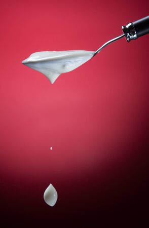 Spoon with yogurt on a red backgroundの写真素材