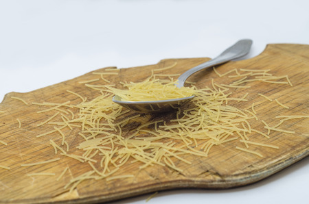 Photo spoon with pasta on a cutting boardの写真素材