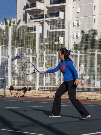 Woman playing tennis on the court and hits the racket on the ballの写真素材