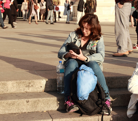 Woman sitting on the stairs reading a message on your mobile phoneの写真素材