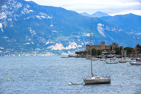 The yacht on the background of the fortress and the mountains in Lake Garda, Italyのeditorial素材