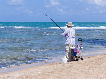 Acre, Israel - May 28, 2016: Elderly man fishing with a fishing rod on the beach in Akre, Israelのeditorial素材