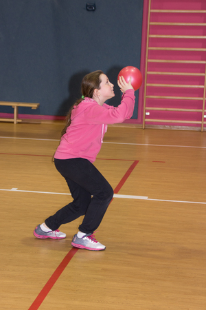 Girl throws a red ball in the basket at the sports hallの写真素材