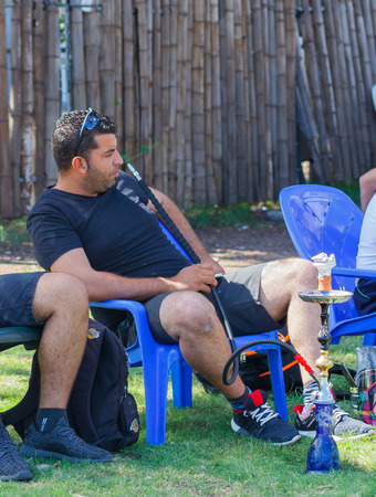 Tiberias, Israel, September 27, 2016: A man sits on a chair and smoking a hookah on rest in Tiberias, Israelのeditorial素材