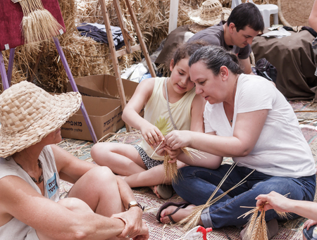 Kibutz Alonim, Israel, June 12, 2016: Woman showing girl how to weave a wreath of ears at the fair in Kibutz Alonim, Israelのeditorial素材