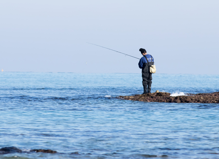 Rosh Hanikra, Israel - February 04, 2017 : Fisherman catches a fish on a spinning at winter morning on the beach near the Rosh Hanikra, Israelのeditorial素材