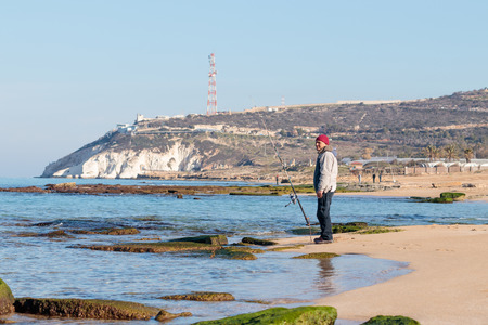 Rosh Hanikra, Israel - February 04, 2017 : Fisherman catches a fish on a spinning at winter morning on the beach near the Rosh Hanikra, Israelのeditorial素材