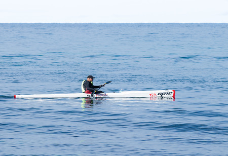 Nahariyya, Israel - February 04, 2017 : Athlete in color tracksuit  training on kayak winter morning on Mediterranean Sea near the coast of Nahariyya, Israelのeditorial素材